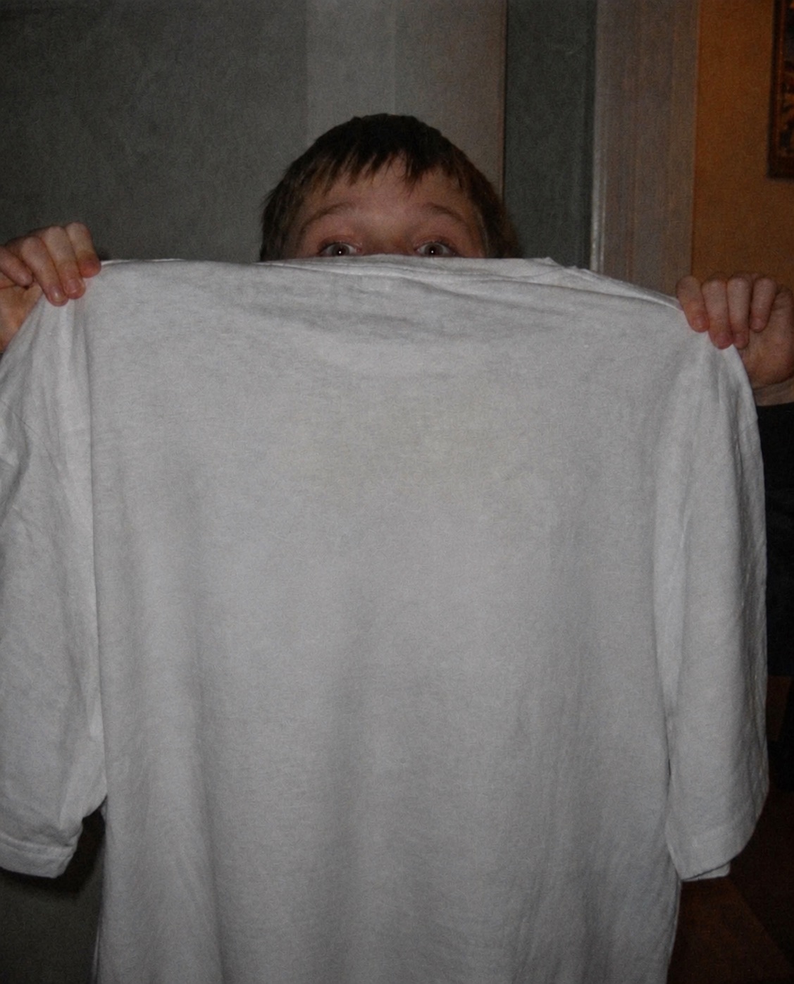 A person peeking over a blank T-shirt